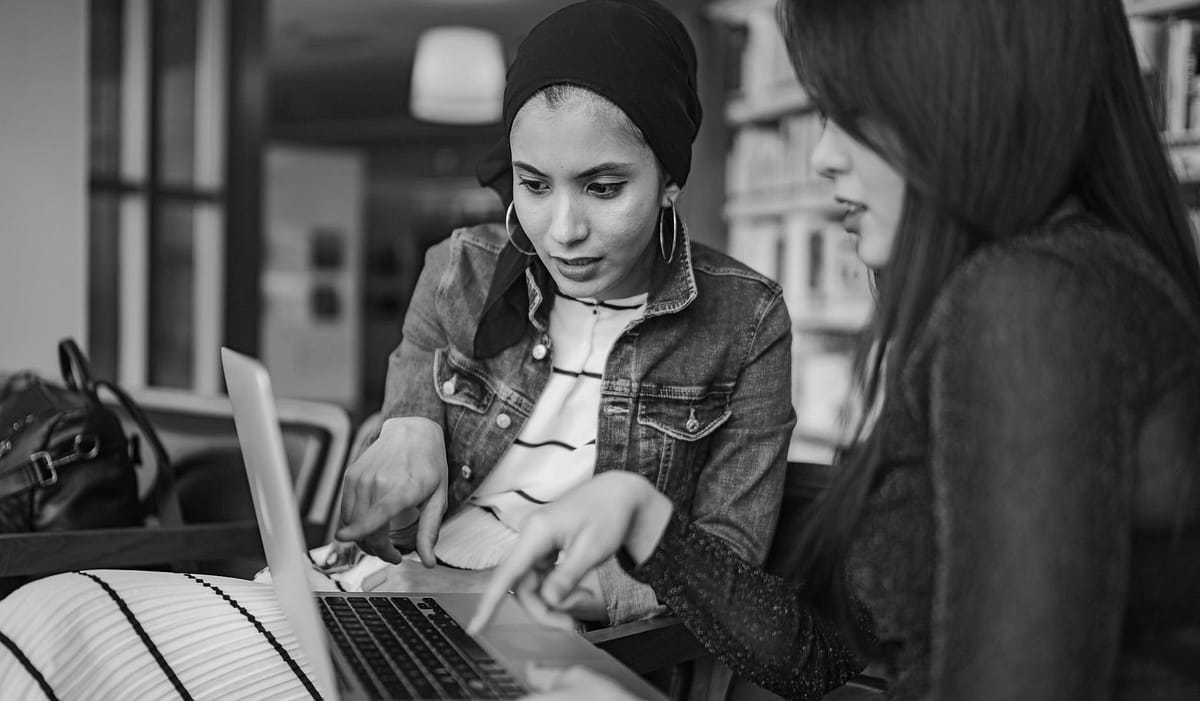 Two young women looking at a laptop and dicussing something
