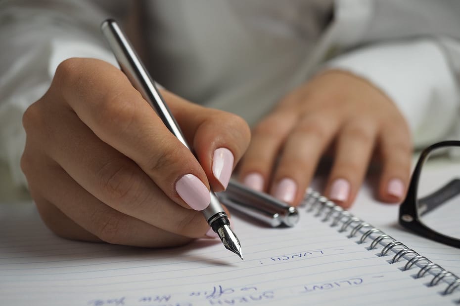 Picture denotes woman drafting text using a pen on paper.